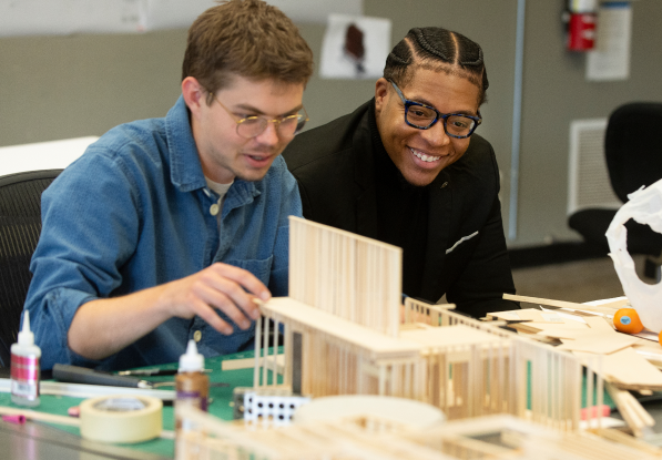 Two architectural students discuss a model.